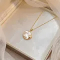 Primo piano del ciondolo della collana dorata con inserto in madreperla, luna e cuore - Luna