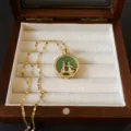 Primer plano de un collar dorado vintage con colgante de jade verde en joyero madera - Estilo Pastor y Tejedora (X0052)