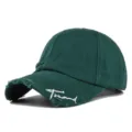 Detailansicht einer dunkelgrünen Baseballkappe im Used-Look mit weißer Trend-Stickerei. - Verwitterte Baseballkappe (20240229) / Dunkelgrün