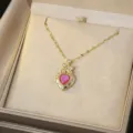 Detailed macro shot of a gold heart pendant with pink stone and small crystals - Pink Enamel Heart Style (X0368-1)
