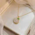 Vue détaillée d'un collier pendentif fleur doré avec zircons blancs et feuille verte - Style Pomme Dorée en Strass (X0888)