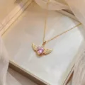 Exquisites Detail einer rosa Herz-Zirkonia-Halskette mit goldenen Engelsflügeln in Box - Rosa Herz Engel Flügel Halskette (X0989)