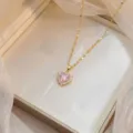 Primer plano de un elegante collar dorado con un colgante de circón rosa brillante en forma de corazón. - Corazón de Circonia Rosa Flor de Cerezo (X0887)
