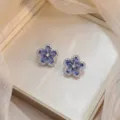 Gros plan sur des boucles d'oreilles fleur avec zircons bleus dans un écrin de luxe - Fleur Bleue (E0192)