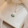 Détail d'un collier avec pendentif fleur composé d'une rose blanche et de feuilles vertes - Rose Sculptée Blanche (X0812)