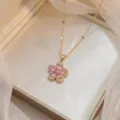 Gros plan d'un collier doré avec pendentif fleur en zircon rose dans son coffret - Style Pétale en Goutte Rose (X0965) / Rose