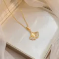 Vue rapprochée d'un pendentif feuille de ginkgo dorée avec pierre jaune et zircons - Style Feuille de Ginkgo Œil de Chat (X0970) / Or