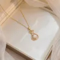 Gros plan d'un collier pendentif sac de chance doré avec zircons et détails de perle - Style Sac de Fortune (X0925)