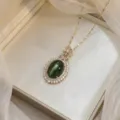 Elegant gold-tone necklace featuring an emerald green oval zircon pendant with floral accents - Oval Dark Green Cluster Flower (X0444)