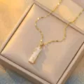 Detailed close-up of a white bamboo node chalcedony pendant on a gold necklace - White Zirconia White Bamboo (X0020)
