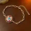 Eleganter goldener Armreif mit rotierender Blumengestalt und bunten Zirkonsteinen - Armband (TS0144) / Gold