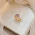 Elegant rotating flower ring with purple zircons and golden finish in jewelry box - Bauhinia Rotating Ring (J0011) / Gold Purple