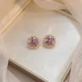 Elegant gold-tone stud earrings featuring rotating purple zircon Bauhinia flower crystal design - Bauhinia Rotating Earrings (E0007) / Gold Purple