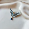 Close-up of elegant blue crystal insect wing brooch on champagne satin fabric background - Blue Wings
