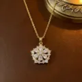 Rotierende goldene Blumenkette mit klaren Zirkonsteinen auf Lederhintergrund - Halskette (X0050) / Gold