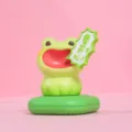 Detail view of a green screaming frog resin figurine fragrance box on a pink background - Happy Frog / Green