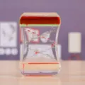 Gros plan d'un sablier à liquide bicolore comme jouet de bureau relaxant - Rouge et Vert