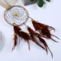 Detailed view of handmade Indian-style dreamcatcher with brown feathers and golden beads - Dark Coffee