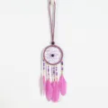 Close-up detail of a handmade purple ethnic dreamcatcher pendant with vibrant pink feathers - Purple
