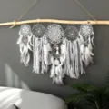 Vue de detail rapprochee d'un attrape-reves blanc en dentelle fait main sur une branche. - Gris / Bâton en bois 50 cm * 50 cm