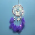 Detailaufnahme des lila Traumfängers mit Federn, LED-Lichtern und dekorativen Ketten. - Hängelampe in Mondlicht-Lila