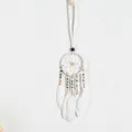 Macro view of a white ethnic-style dreamcatcher pendant with delicate feathers and beads - White
