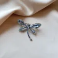 Detailed macro shot of an elegant dragonfly brooch with blue and purple crystals - Blue Dragonfly