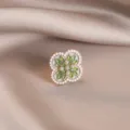 Detailed macro view of an elegant green enamel flower brooch with pearl accents on satin - 745#绿色四叶草