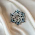 Detailed macro view of an elegant silver floral wreath brooch with blue marquise crystals - 881#
