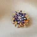 Elegant flower brooch featuring marquise-cut purple crystals and gold plated metal petals - Purple