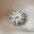 Elegant silver flower pin with marquise crystals displayed on a champagne silk - Silver