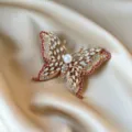 Luxurious gold butterfly brooch with pink crystals and pearl on champagne silk fabric. - Single Pearl Center Layered Butterfly Style (907)