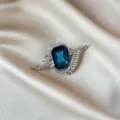 Detailed close-up shot of elegant blue crystal rhinestone brooch on smooth satin background. - 882#