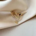 Detail macro of a gold hollow hummingbird brooch on champagne satin fabric texture. - Hollow Hummingbird Style (835) / Hollow Bird