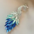Elegant peacock brooch with blue and clear crystals shown on a textured grey fabric - Blue Malachite