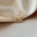Close-up of a gold steering wheel brooch with sparkling rhinestones on satin - Ship's Wheel Style (852) / Gold/White