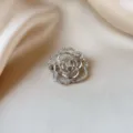 Elegant silver camellia flower brooch with shiny rhinestones on silk fabric background. - Camellia Style (896) / Silver With White Zirconia