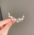 Close-up of elegant crescent pearl brooch with sparkling zirconia, delicate suit accessory. - Gold