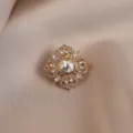 Detailed close-up of a vintage gold-toned crystal floral brooch sparkling rhinestones accessory. - White Flower