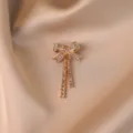 Gold crystal bow brooch with hanging tassels, elegant accessory for coats and dresses. - Bow / Gold