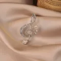 Detailed view of an elegant musical note brooch with sparkling clear crystals on satin - Music Note / Silver