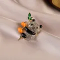 Macro view of a sparkling rhinestone panda brooch with enamel bamboo and persimmons - Panda / Gold