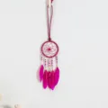 Vue détaillée d'un pendentif attrape-rêves rose de style ethnique avec plumes et perles - Rose Violet