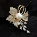 Close-up detail of the luxury pearl and crystal brooch featuring exquisite paved zirconia on golden metal. - Flower