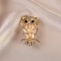 Close-up detail of the elegant gold owl brooch, sparkling crystal rhinestones, and delicate branch design. - Owl / Gold