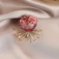 Detail view of crystal floral brooch, pink heart resin flower with sparkling rhinestones and gold rays. - Burgundy