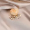 Close-up of a sparkling floral brooch featuring translucent resin petals and crystal rhinestones. - Orange
