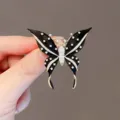 Elegant black enamel butterfly brooch with sparkling crystals and gold-tone metal frame. - Black Butterfly Pendant
