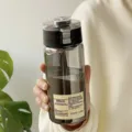 Gedetailleerd zicht op een minimalistische rookgrijze waterfles met etiket in de hand - 550 ml zwart van kwaliteit
