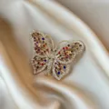 Elegant gold-toned butterfly brooch with multi-colored crystals on satin background - Hollow Colorful Butterfly Style (906)